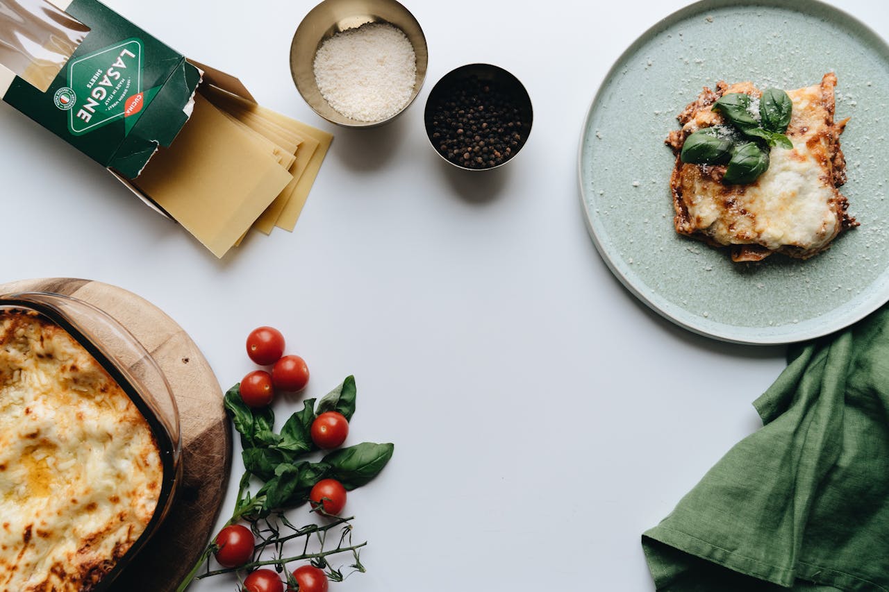 Delicious homemade Italian lasagna with fresh tomatoes and basil, styled on a white background.